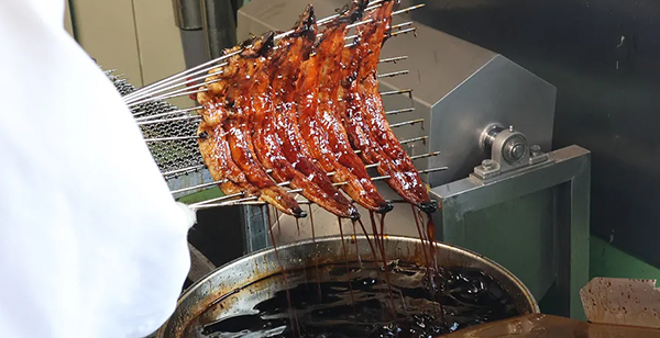 秘伝のタレに何度もくぐらせて重ね焼きする工程